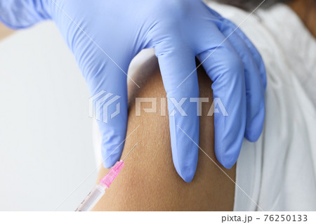 Doctor injecting medicine in patient shoulder closeup Doctor injecting medicine in patient shoulder closeup 76250133