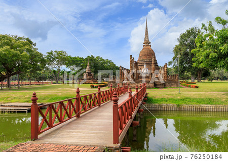 Red wooden bridge across the pond leading to pagoda and ruined chapel monastery complex at Wat Sa Si temple, Sukhothai Historical Park, Thailand Red wooden bridge across the pond leading to pagoda and ruined chapel monastery complex at Wat Sa Si temple, Sukhothai Historical Park, Thailand 76250184