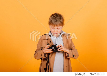 Child boy red head photographer with retro photocamera in studio 76250602