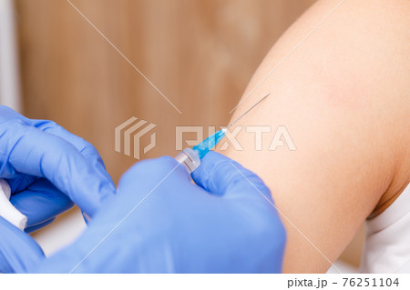 Doctor injecting a vaccine in arm close-up 76251104