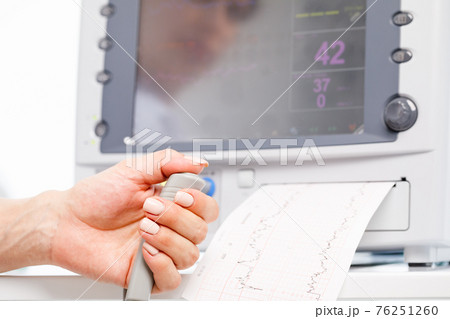 Pregnant woman performing cardiotocography CTG monitoring fetal heartbeat close-up 76251260