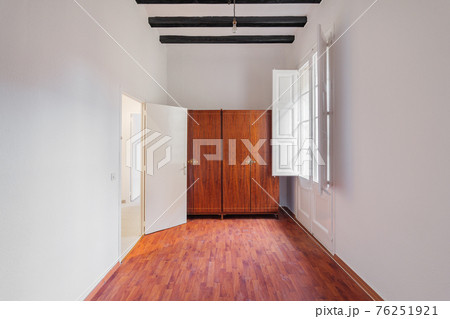 White room interior with wooden wardrobe, black beams, window and boot marks on the parquet White room interior with wooden wardrobe, black beams, window and boot marks on the parquet 76251921