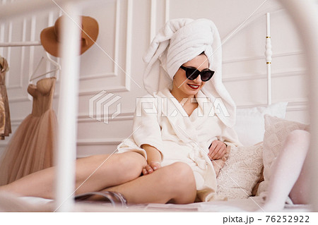 Glamorous young woman with sunglasses, a white bathrobe and with a towel 76252922