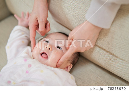 ほっぺを突かれ笑うアジア人の赤ちゃんの写真素材