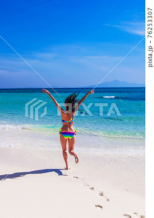 Happy girl running to tropical sea 76253307