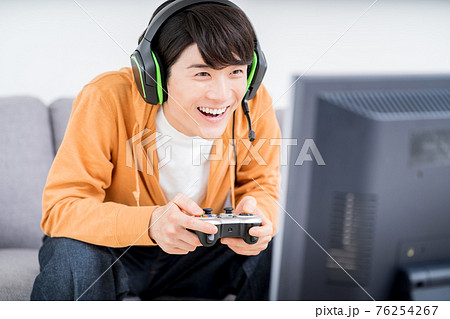 部屋でネットゲームをプレイする男性 76254267