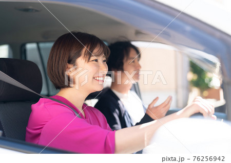 車を運転する若い女性 76256942