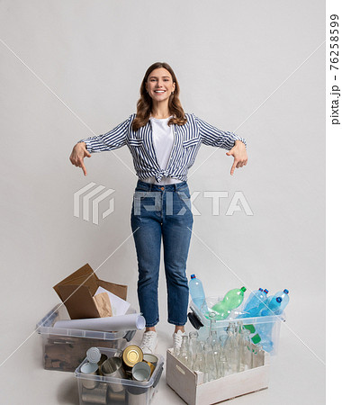 Young lady sorting waste, pointing at containers with different kind of garbage 76258599