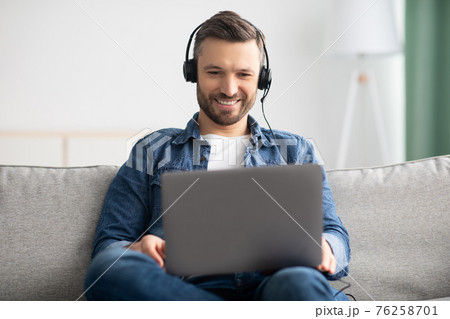 Relaxed man watching movie, using laptop and headphones Relaxed man watching movie, using laptop and headphones 76258701
