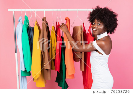 African Lady Picking Clothes Posing Near Clothing Rail, Pink Background African Lady Picking Clothes Posing Near Clothing Rail, Pink Background 76258726