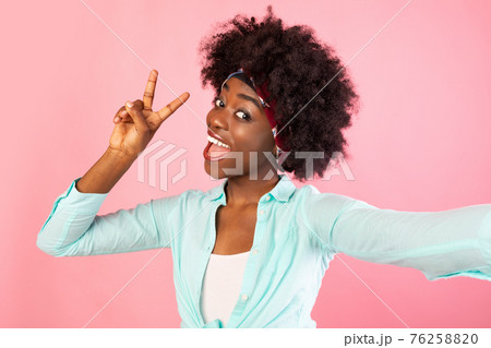 Bushy African Woman Making Selfie Posing Gesturing V-Sign, Pink Background Bushy African Woman Making Selfie Posing Gesturing V-Sign, Pink Background 76258820