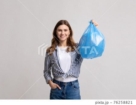 Portrait Of Smiling Millennial Lady Carrying Blue Plastic Waste Bag Portrait Of Smiling Millennial Lady Carrying Blue Plastic Waste Bag 76258821