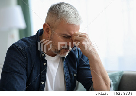 Exhausted matured man touching his nose bridge, home interior Exhausted matured man touching his nose bridge, home interior 76258833