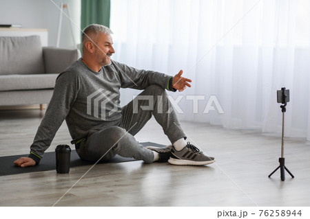 Handsome senior man fitness coach broadcasting from home Handsome senior man fitness coach broadcasting from home 76258944