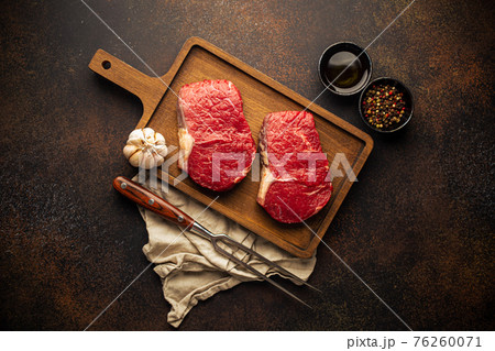 Two raw meat steaks on wooden board 76260071