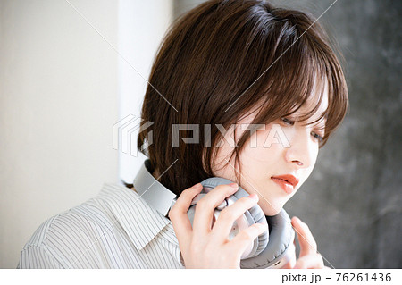 ヘッドフォンを外して首にかける女性 76261436