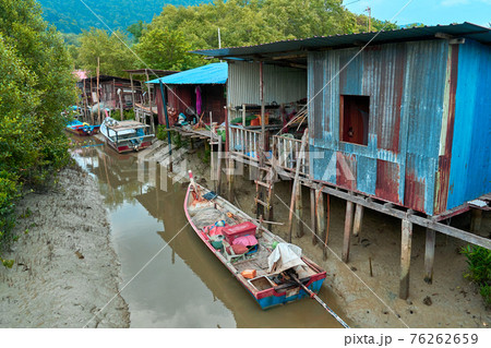 Fishermen's village in Asia. Boats near dilapidated houses on stilts Fishermen's village in Asia. Boats near dilapidated houses on stilts 76262659