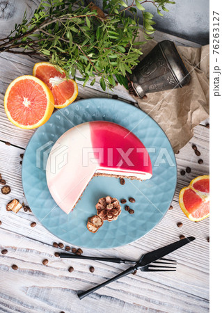 Red and white cake with orange filling. Nearby on a black table are ingredients oranges, nuts. Rustic style. 76263127