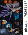 Blue cake filled with orange and tangerine in the shape of a cube. Nearby on a black table are ingredients oranges, tangerines, nuts. Rustic style 76263137