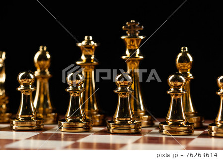 Golden chess figures standing on chessboard Golden chess figures standing on chessboard 76263614