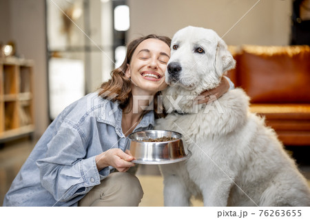 Woman feeding dog with a dry food at home Woman feeding dog with a dry food at home 76263655