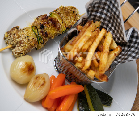 Lamb skewer with sesame seeds, served with fries, carrot, zucchini and white onions Lamb skewer with sesame seeds, served with fries, carrot, zucchini and white onions 76263776