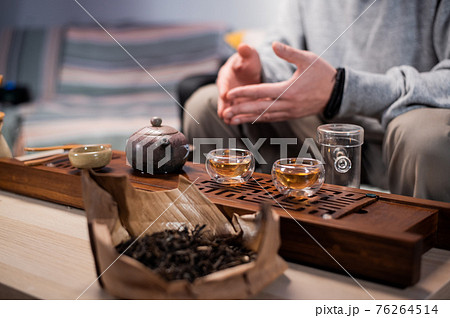 Close-up of the chinese tea ceremony ritual. Hands pour hot water into special vessels on a bamboo board. 76264514