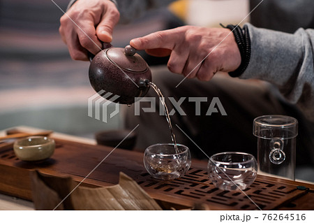 A man treats a guest to authentic ripe vietnamese tea on a special gongfu board made of bamboo. Traditions of eastern tea drinking. 76264516