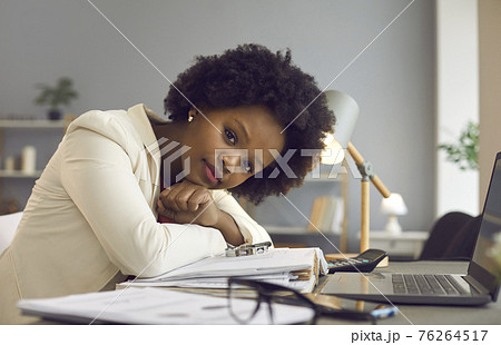 Portrait of successful young businesswoman sitting at office desk and looking at camera 76264517