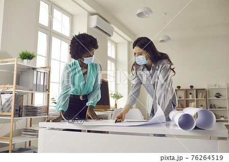Two architects ot designers wearing face masks working on project in their office Two architects ot designers wearing face masks working on project in their office 76264519