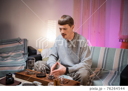 A young adult man learns the art of meditation during a tea ceremony to relax and enjoy the natural aroma of chinese black raw tea. A young adult man learns the art of meditation during a tea ceremony to relax and enjoy the natural aroma of chinese black raw tea. 76264544