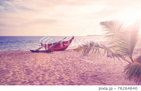 Small boat on an empty beach at sunset, color toning applied, Sri Lanka. 76264640