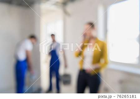 Blurred background of builders are renovating a room, a woman speaks on the phone 76265181