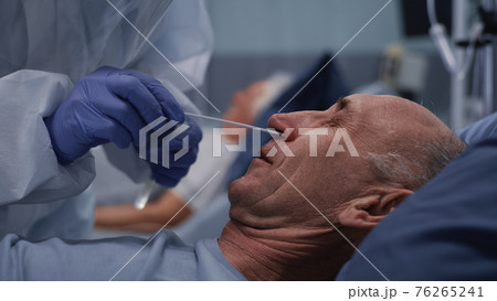 Crop doctor taking coronavirus test from senior patient 76265241