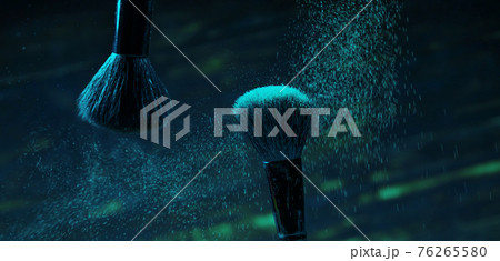 explosion of green and blue eyeshadows on dark background. makeup brushes explosion of green and blue eyeshadows on dark background. makeup brushes 76265580