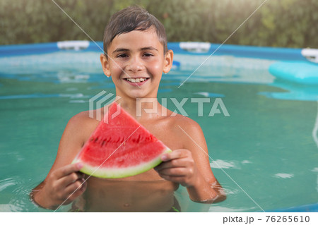 happy boy swims in the pool, holds a slice of watermelon, smiling, summer and travel concept happy boy swims in the pool, holds a slice of watermelon, smiling, summer and travel concept 76265610