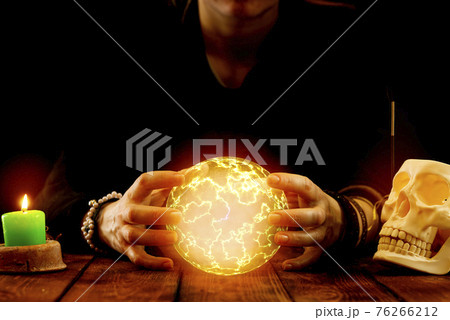 A fortune-teller or oracle with objects for fortune-telling holds a fireball in his hands to predict the future during the session. Psychic readings and the concept of clairvoyance 76266212