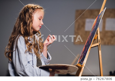 An art school student mixes colors on a palette for her canvas drawing in a workshop. 76267806