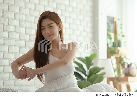 Asian women wake up happy and smile on white bed in bedroom. Asian women wake up happy and smile on white bed in bedroom. 76268667