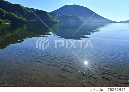 中禅寺湖千手ヶ浜と男体山に湖面に映る太陽 76272945