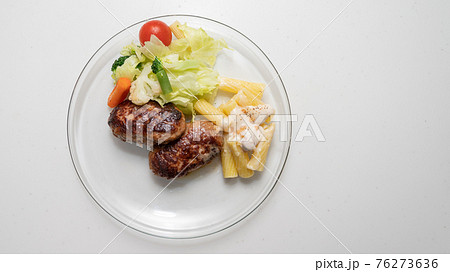 ハンバーグと野菜を透明なお皿の上に 76273636