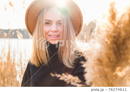 European blonde woman with beige hat in black sweater in the countryside. Golden hour, cottagecore. Local travel. Slow living. Mental health. Pampas grass European blonde woman with beige hat in black sweater in the countryside. Golden hour, cottagecore. Local travel. Slow living. Mental health. Pampas grass 76274611