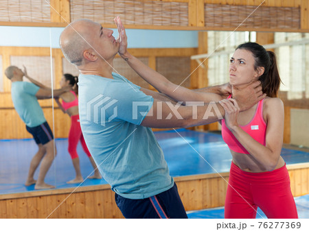 Woman is training with man on the self-defense course in gym 76277369