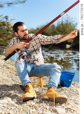 Bearded fisherman prepares fishing gear 76277679