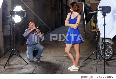 Professional man photographer working with smiling model on city street 76277805