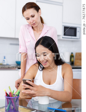 Mother looking into smartphone Mother looking into smartphone 76277875