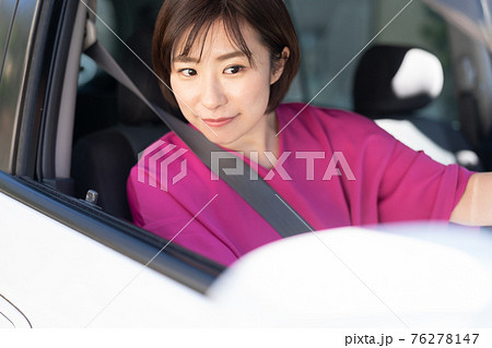 車を運転する若い女性 76278147