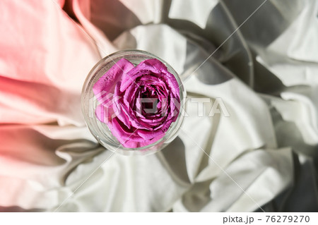 Wine glass filled with pink flower petalson on white silk fabric. Minimal modern still life. Holiday concept Valentines or womans day background design Wine glass filled with pink flower petalson on white silk fabric. Minimal modern still life. Holiday concept Valentines or womans day background design 76279270
