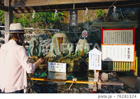 【三重】初夏の伊勢　二見興玉神社の手水舎の蛙と参拝する女性 76281324