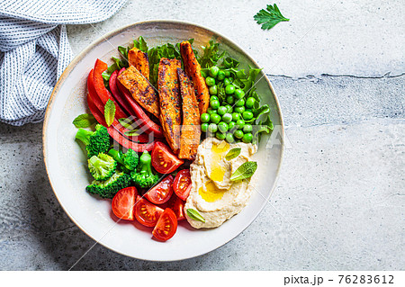 Vegan salad bowl with sweet potatoes, broccoli, tomato, peas and hummus. 76283612